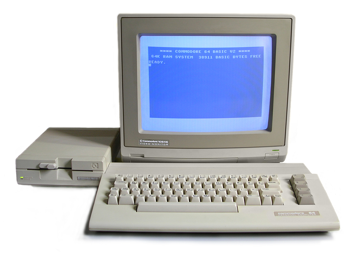 A Commodore 64C computer with a 1541-II floppy drive and a Commodore 1084S monitor, showing the classic blue BASIC READY prompt on screen